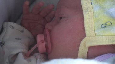 Yeni doğmuş bebek suratı. Aç gözlerini. Pembe emzik ile. Makro görünümü kapat.