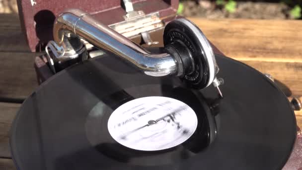Antiguo fonógrafo de gramófono marrón pequeño al aire libre. disco de vinilo girando. de cerca — Vídeo de stock
