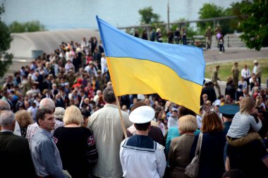 Kherson, Ukrayna - 9 Mayıs 2016: Ukrayna ulusal bayrağı dalgalanırken, Zafer Günü anısına büyük bir kalabalık toplandı. Halk törenine aileler ve üniformalı insanlar da dahil olmak üzere izleyiciler katılıyor..