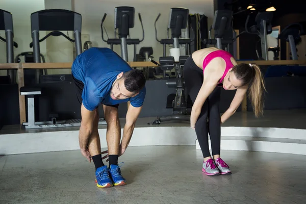 Man and woman doing stretches at the gym — Stock Photo, Image