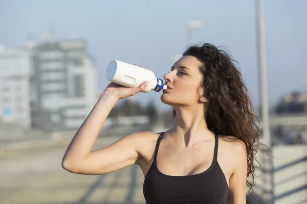 Jonge vrouw die water drinkt na inspanning — Stockfoto