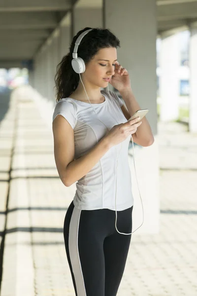 Fitness meisje luisteren naar muziek tussen de trainingen — Stockfoto