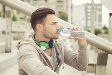 İçme suyu ve egzersiz arasında oturan genç adam