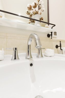 Banyo içi beyaz lavabo ve muslukla dolu.