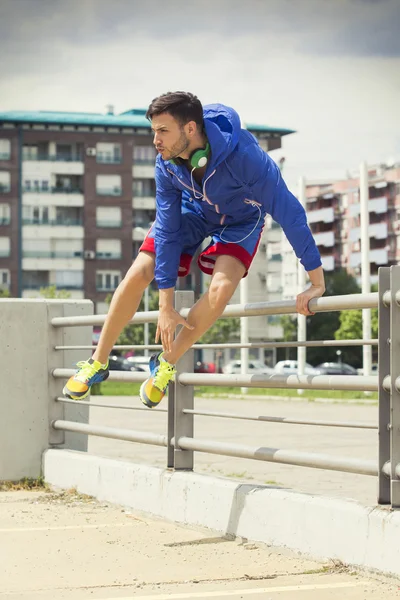 Knappe jonge atleet over het hek springen — Stockfoto