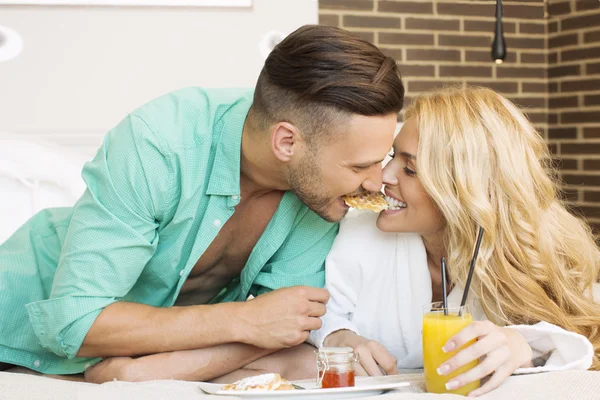 Glada lekfulla par med frukost i sängen — Stockfoto