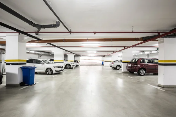 Estacionamiento subterráneo, interior con algunos coches aparcados . — Foto de Stock