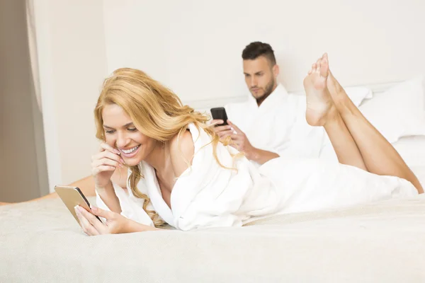 Pareja en la cama, usando teléfonos inteligentes —  Fotos de Stock