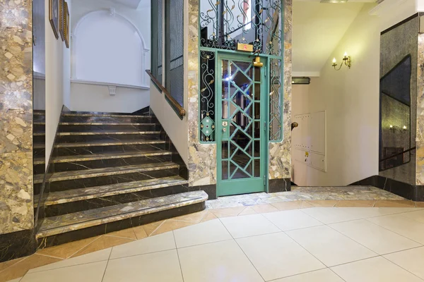 Interior of a corridor with passenger lift and marble stairs — Stock Photo, Image
