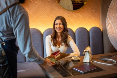 Garson, genç ve mutlu bir bayana meyveli kek ikram ediyor.