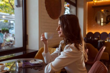 Muhteşem genç bayan restoranda tek başına kahve içiyor.