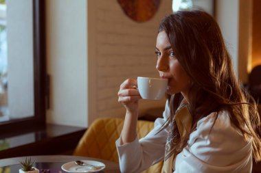 Muhteşem genç bayan restoranda tek başına kahve içiyor.
