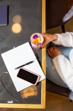 Restoranda çiçeklerle süslenmiş smoothie içen bir kadının en iyi görüntüsü.