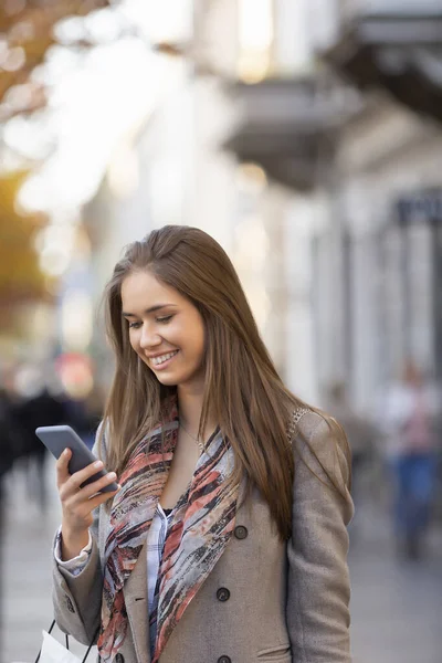 Güzel Genç Bir Kadın Sokakta Akıllı Telefon Kullanıyor Gülümsüyor — Stok fotoğraf
