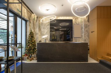 Otel resepsiyonunda resepsiyon masası ve süslü Noel ağacı.
