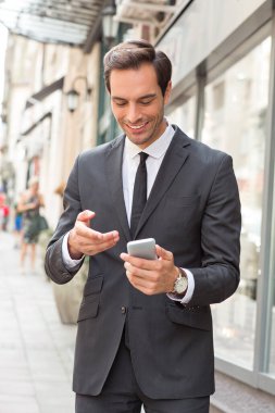 Takım elbiseli bir işadamı dışarıda cep telefonuyla konuşuyor.