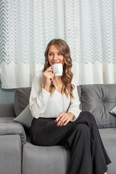 迷人的女人坐在沙发上喝咖啡 — 图库照片