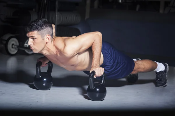Άνθρωπος που κάνει push-ups με kettlebells στο γυμναστήριο — Φωτογραφία Αρχείου
