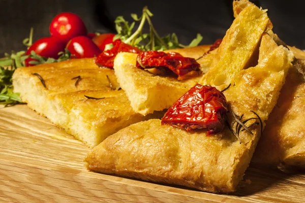 Maïsbrood op een houten bord met gedroogde tomaten en kersen tomatoe — Stockfoto