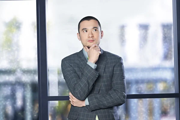 Geschäftsmann mit der Hand am Kinn, den Blick nach oben gerichtet — Stockfoto