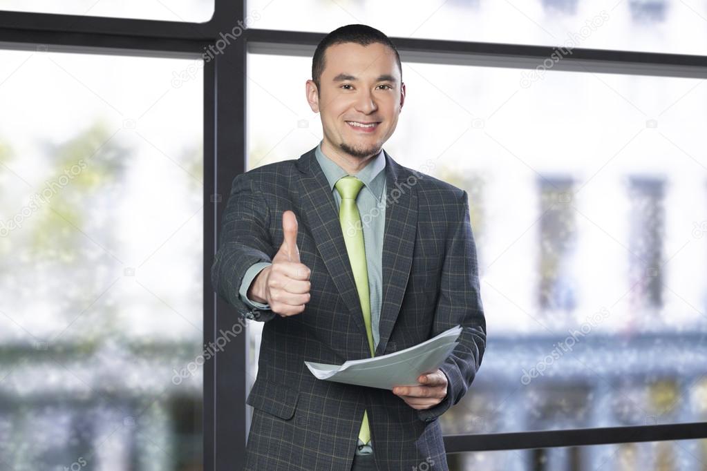 Businessman holding documents and giving thumbs up