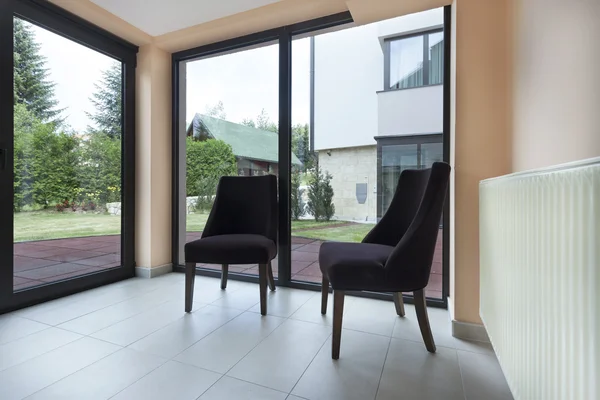 Twee stoelen in een kamer met grote ramen — Stockfoto