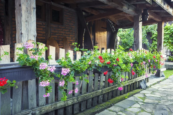 Antiguo patio de la casa con flores en valla de madera — Foto de Stock