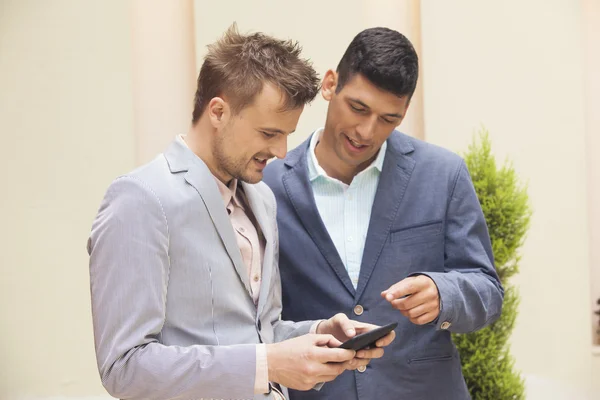 Two businessmen looking at tablet and talking