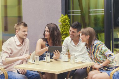 Tablet kafede fotoğraflara bakarken arkadaşlar