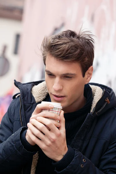 Jonge man buitenshuis op een koude dag met warme dranken — Stockfoto