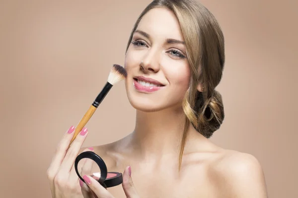 Mulher bonita aplicando blush — Fotografia de Stock