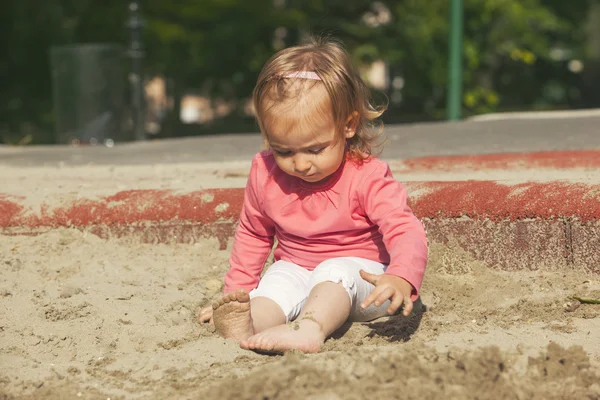 小さな女の子が砂で遊んで — ストック写真