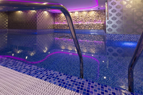 Indoors pool with colorful lights at spa center — Stock Photo, Image