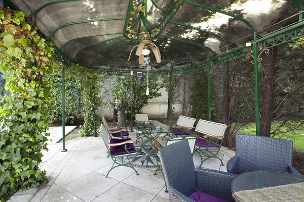Lusthus i trädgård med bord och stolar — Stockfoto