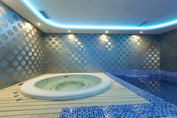 Jacuzzi interior y piscina con luces de colores en el centro de spa — Foto de Stock