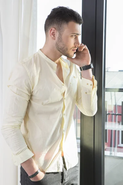 Handsome man on the phone looking through window — Stock Photo, Image