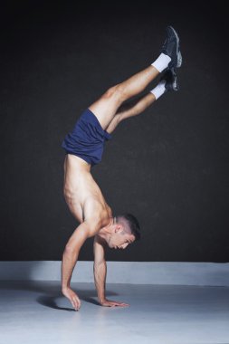 Muscular athlete doing a one arm handstand