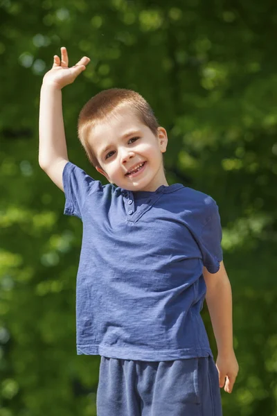 Cute boy outdoors, raised hand — Stock Photo, Image