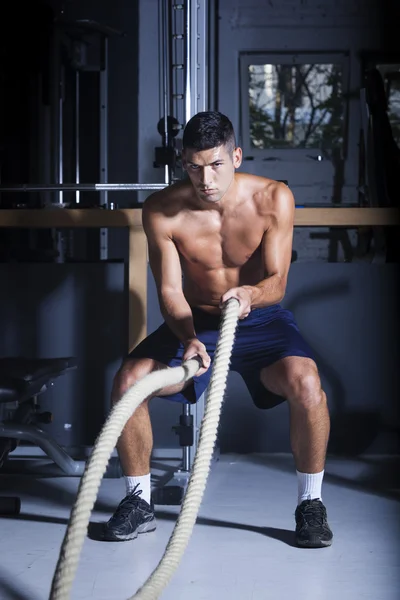 Homem musculoso no ginásio com cordas de batalha — Fotografia de Stock