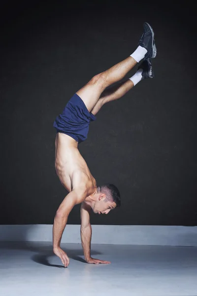 Muscular athlete doing a one arm handstand — Stockfoto