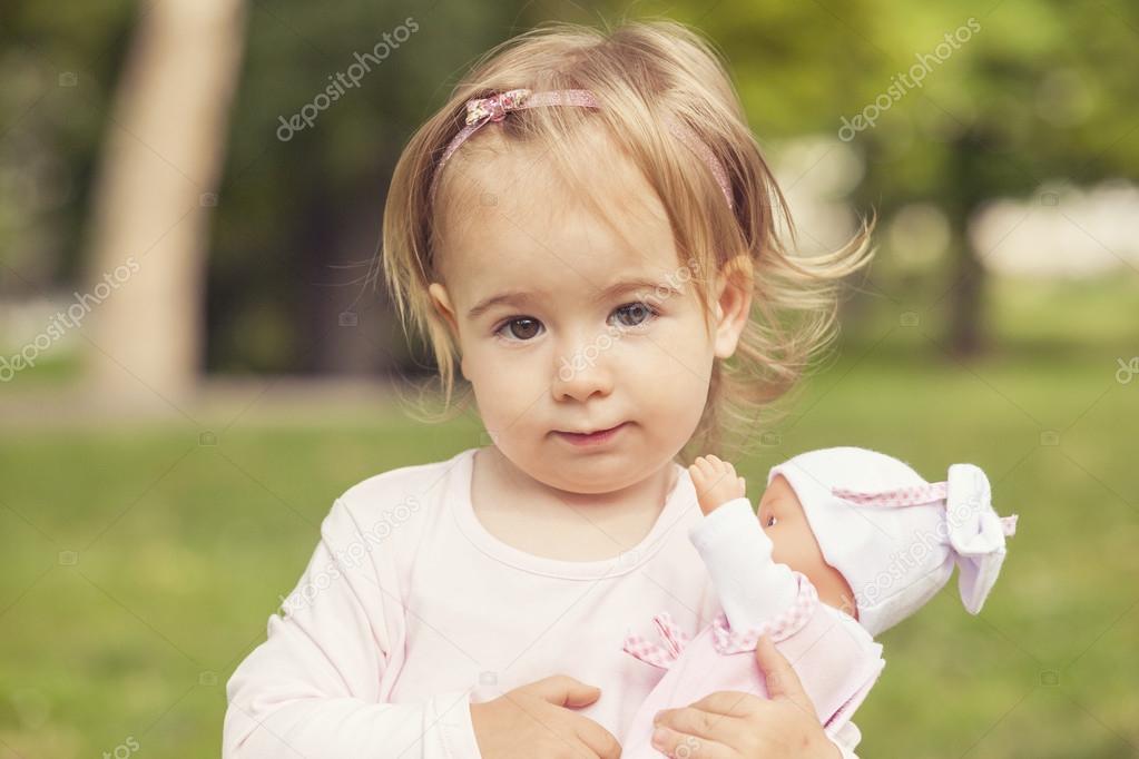 Cute girl holding a doll baby outdoors