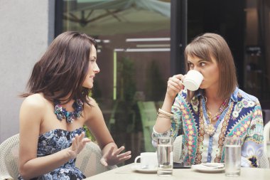 Two girlfriends gossiping in cafe