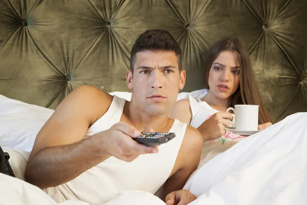 Мужчина смотрит телевизор, в то время как его девушка выглядит раздраженной — стоковое фото