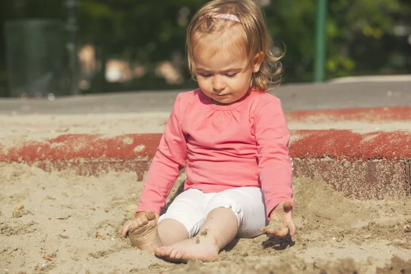 小さな女の子が砂で遊んで — ストック写真