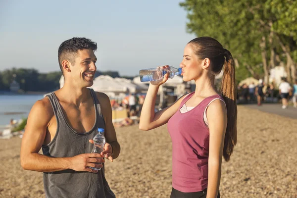 Man en vrouw drinkwater na het joggen — Stockfoto