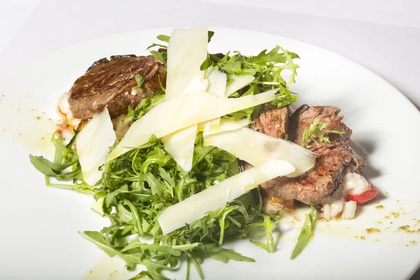 Bife de vaca servido com rúcula, queijo e risoto — Fotografia de Stock