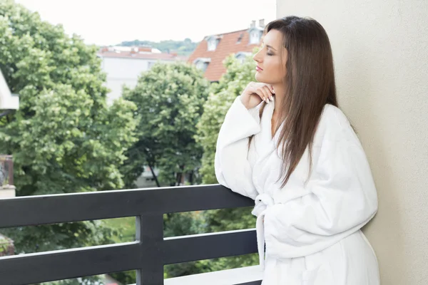 Junge Frau schaut vom Balkon nach draußen — Stockfoto