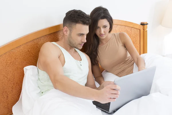 Pareja en la cama mirando a la computadora portátil juntos —  Fotos de Stock