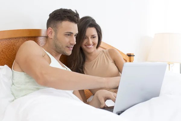 Paar schaut gemeinsam auf Laptop im Bett — Stockfoto