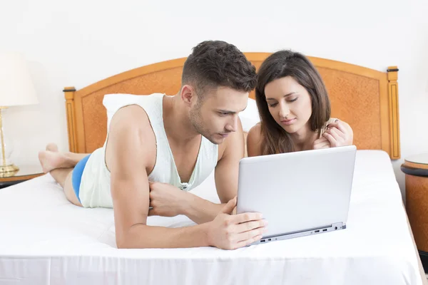 Casal na cama olhando para laptop juntos — Fotografia de Stock